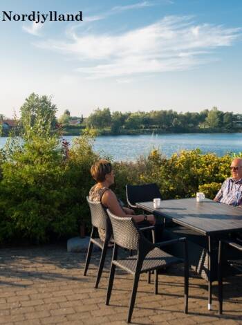 Rum med utsikt över gårdsplanen eller mot Aabybro-sjö och naturområdet.
