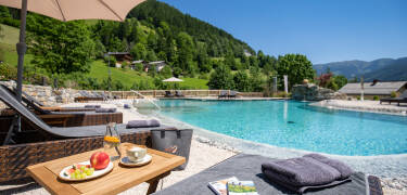 Genießen Sie die Sonne und den Blick auf die bergige Landschaft am gemütlichen Pool.
