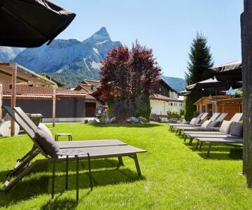 Genießen Sie das atemberaubende Alpenpanorama und entspannen Sie im sonnigen Hotelgarten.