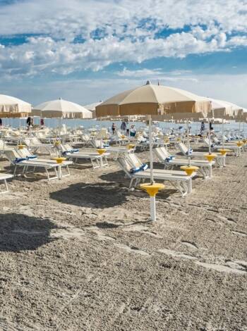 Hotellets privata strand med solstolar och parasoller passar perfekt för en sommarsemester.