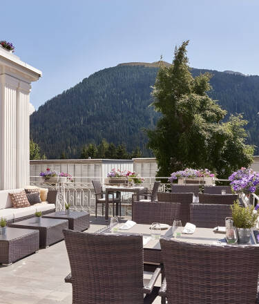 Slå dig ner på hotellets inbjudande solterrass och njut av något gott att dricka med en vidsträckt utsikt över bergen runt Davos.