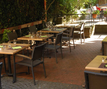 Genießen Sie ein Glas Wein auf der gemütlichen, mit duftenden Blumen geschmückten Terrasse des Hotels.