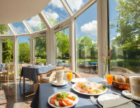 Beginnen Sie Ihren Tag mit einem reichhaltigen Frühstücksbuffet und genießen Sie den Blick auf den Garten vom Frühstücksraum des Hotels.