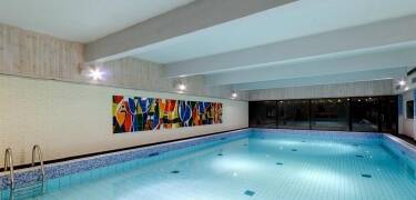 Entspannen Sie im Wellness-Bereich des Hotels mit Schwimmbecken, Dampfbad und Sauna mit Aussicht auf den Berg.
