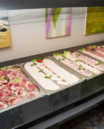 Each morning begins with a generous breakfast buffet offering a varied selection of fresh bread, cold cuts, fruit, and hot drinks.