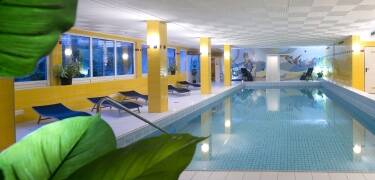 Der Wellnessbereich umfasst ein großes Hallenbad, Sauna, Dampfbad und einen Ruheraum mit Liegen.