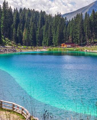 Besøk Montagnoli-sjøen, kjent for sitt turkisblå vann og perfekte sted for en avslappende piknik i et fantastisk naturlig solarium i Dolomittene.