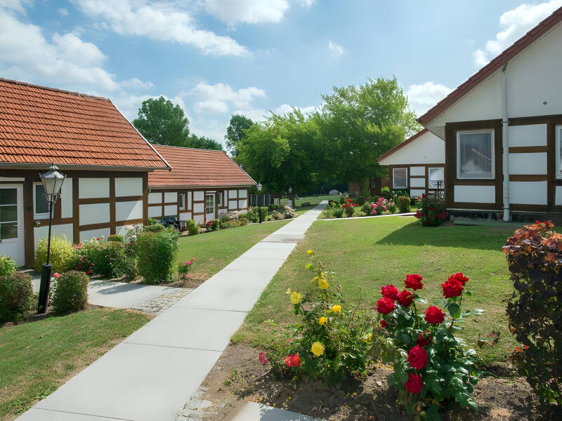 Buchen Sie einen entspannten Aufenthalt in einem charmanten Feriendorf mit Gebäuden im traditionellen Stil und grünen Rasenflächen.