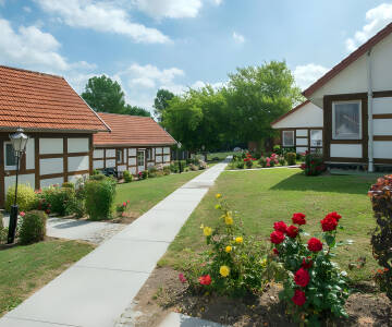 Book et afslappende ophold i en hyggelig ferieby med traditionelle bygninger og grønne græsplæner.