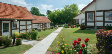 Book et afslappende ophold i en hyggelig ferieby med traditionelle bygninger og grønne græsplæner.