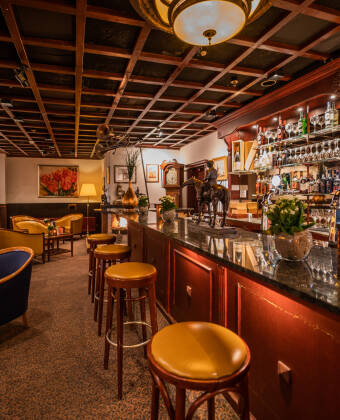 Den charmerende bar med pejs tilbyder en afslappende atmosfære for en kop kaffe, en drink eller et let måltid.